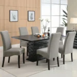 An angled view of the 7-piece dining room set, focusing on the unique pedestal table base and the upholstered chairs.