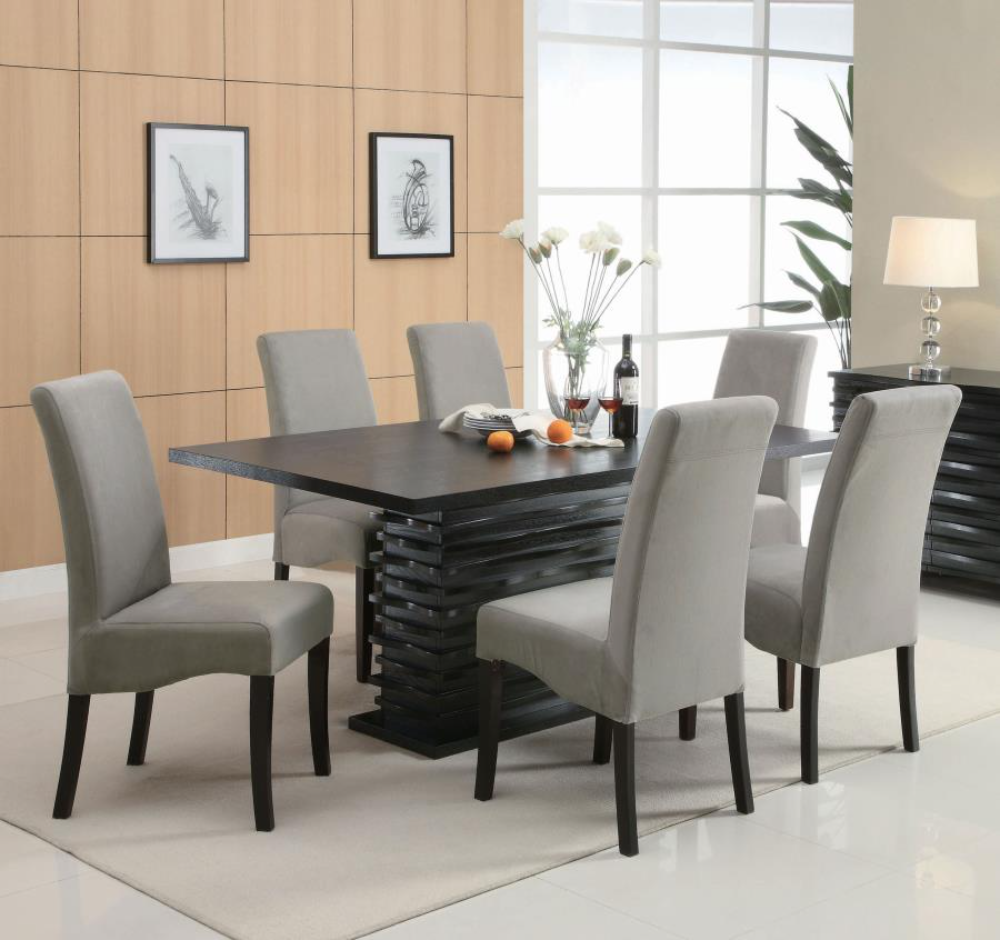 An angled view of the 7-piece dining room set, focusing on the unique pedestal table base and the upholstered chairs.