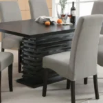 A contemporary black dining table with a unique layered pedestal base in a stylish dining room.