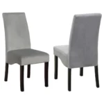 A side view of the grey upholstered dining chair with black legs, emphasizing its elegant shape and tailored details.