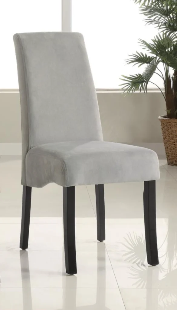 A grey velvet upholstered dining chair with a flared back and black legs.