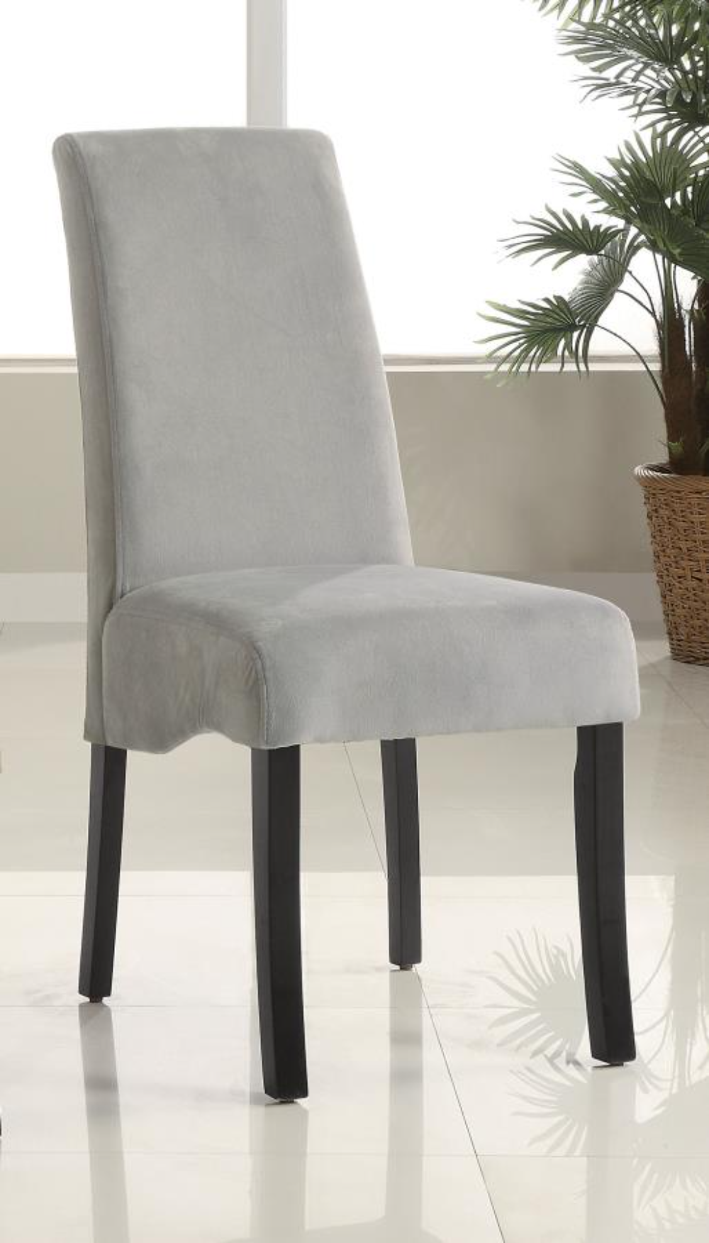 A grey velvet upholstered dining chair with a flared back and black legs.
