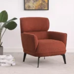 An angled view of the orange upholstered chair, emphasizing the curve of the arms and the black legs.