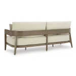 Angled back view of Amos 3 seater outdoor sofa showing curved wood-look aluminum frame, cream cushions, and tapered legs on white background