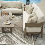 Overhead view of Amos outdoor sofa set with loveseat, coffee table, decorative vases, and geometric outdoor rug near pool
