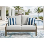 Milas beige aluminum outdoor loveseat styled on a patio with a blue patterned rug and pool in the background
