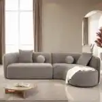 A contemporary Revello sectional sofa in light brown chenille with a curved design and accent pillows.