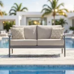 Akcay gray aluminum outdoor loveseat styled on poolside patio with modern home and tropical landscaping