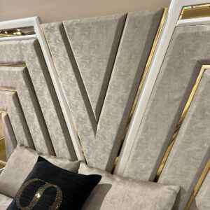 Close-up of a luxurious bed headboard with a modern V-shaped design featuring gold accents and high-quality fabric.