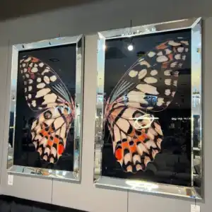 Large two-panel Butterfly Wall Art with a black background and mirrored border frames. This elegant modern home accessory is displayed at the home decor store in Tampa, De'Luxe Home Decor & Furniture.