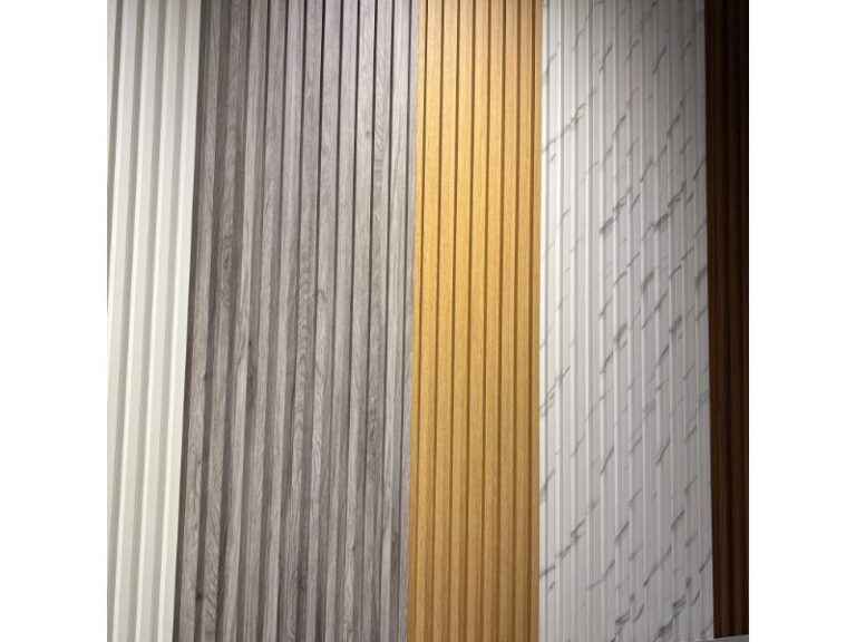 Modern fluted wall panels in various finishes, including WPC and PVC materials, displaying white marble, natural oak wood grain, and gray textures available at Deluxe Home Decor & Furniture Tampa.