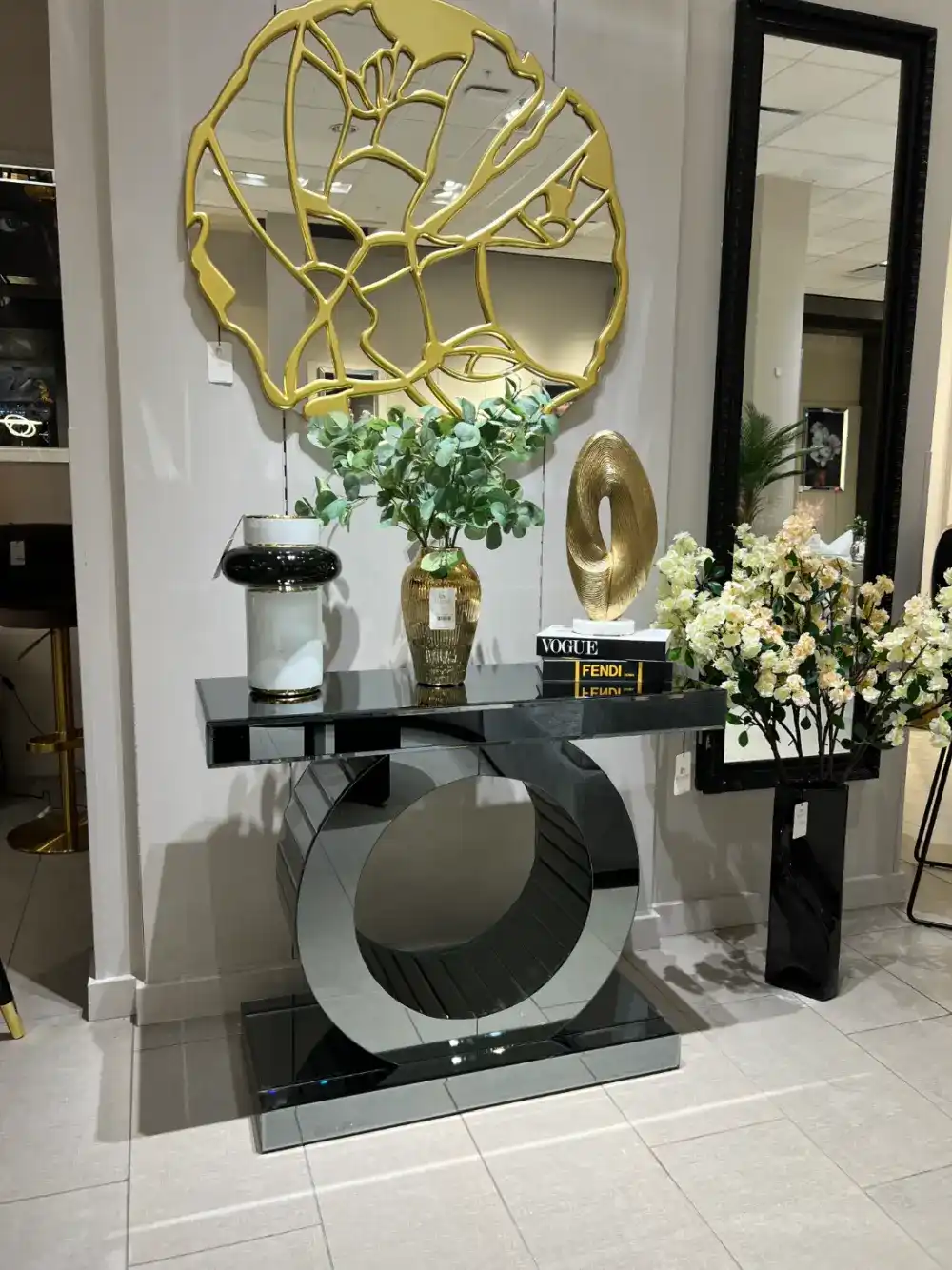World Console Gray Mirrored Console Table with sculptural circular base, styled with modern decor books and a gold accent mirror.