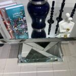 N-shaped silver mirrored console table adorned with decorative accessories, enhancing a chic entryway.