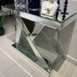 N-shaped silver mirrored console table adorned with decorative accessories, enhancing a chic entryway.