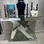 N-shaped silver mirrored console table adorned with decorative accessories, enhancing a chic entryway.