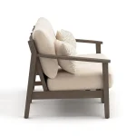 Side profile of Patara wood Outdoor loveseat with Beige Cushions depth, dark brown armrest, and patterned accent pillow