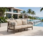 Patara acacia wood outdoor sofa with beige cushions styled on a luxury stone patio next to an infinity pool and modern home