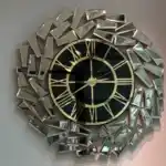 An large gold wall clock with a black face and golden mirrored panels in an abstract geometric design.