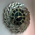A gold and black wall clock with a black face and golden mirrored panels in an abstract geometric design.