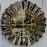 A wall clock with a bronze mirrored frame, a black face, and Roman numeral wall clock design.