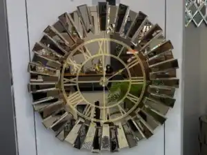 A wall clock with a bronze mirrored frame, a black face, and Roman numeral wall clock design.