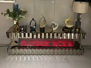 A 79-inch bronze mirrored fireplace TV stand with an electric fireplace glowing red, decorated with various gold and white accessories.