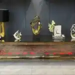 A low, angled view of a bronze curved mirrored TV stand showing the red-glowing fireplace and its reflective surface.