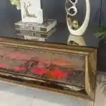 n angled frontal view of a curved bronze mirrored TV stand with a red-glowing electric fireplace and sleek golden legs.