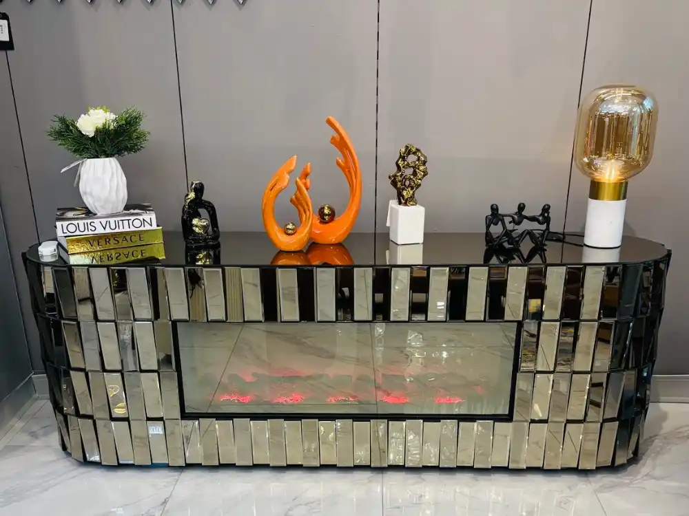 A bronze mirrored TV stand with a purple glowing electric fireplace and a remote control on the bottom shelf.