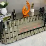 A close-up side view of a bronze mirrored TV stand, showing its geometric panels and the purple light from the electric fireplace.