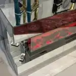 A close-up side view of a silver mirrored TV stand's red glowing fireplace, with a remote control visible on the mirrored shelf.