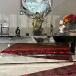 A silver mirrored fireplace TV stand with a tiered, U-shaped design and a red glowing fireplace.
