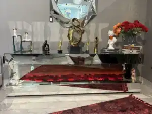 A silver mirrored fireplace TV stand with a tiered, U-shaped design and a red glowing fireplace.