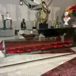 A close-up angled shot of a silver mirrored fireplace TV stand, focusing on the vibrant red fireplace.