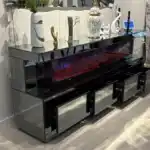 A dark gray mirrored TV stand with a red and purple electric fireplace, decorated with various home accessories.