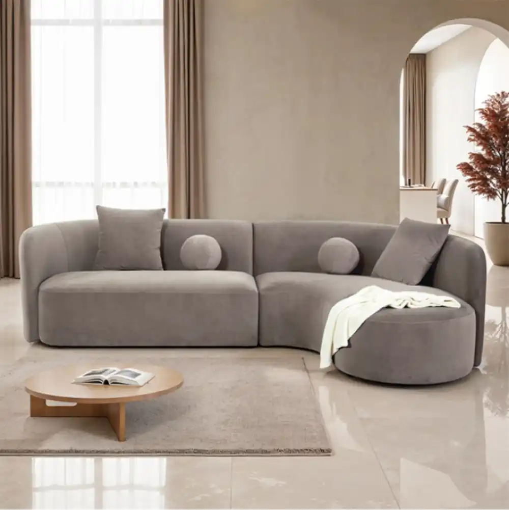 A contemporary Revello sectional sofa in light brown chenille with a curved design and accent pillows.