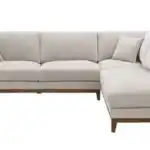 A stylish Watton Mid-Century Modern sectional sofa in light gray chenille fabric, featuring a right chaise and warm walnut tone wood trim, set in a bright living room.