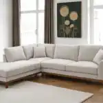 A stylish Watton Mid-Century Modern sectional sofa in light gray chenille fabric, featuring a left chaise and warm walnut tone wood trim, set in a bright, contemporary living room.