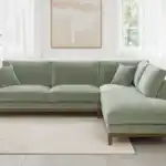A contemporary Watton Mid-Century Modern sectional sofa in olive green chenille fabric, featuring a right chaise and warm walnut tone wood trim, set in a bright living room.