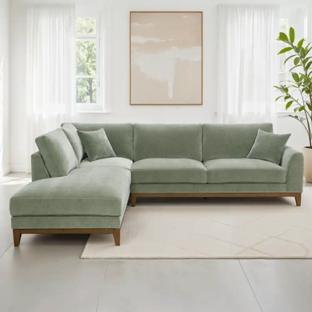 A contemporary Watton Mid-Century Modern sectional sofa in olive green chenille fabric, featuring a left chaise and warm walnut tone wood trim, set in a bright living room.