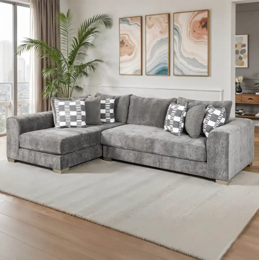 A wide Artesia transitional sectional sofa in charcoal gray fabric, with a chaise lounge, track arms, and decorative throw pillows in a modern living room setting.