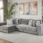 A wide Artesia transitional sectional sofa in charcoal gray fabric, with a chaise lounge, track arms, and decorative throw pillows in a modern living room setting.