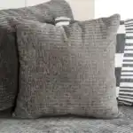 A wide Artesia transitional sectional sofa in charcoal gray fabric, with a chaise lounge, track arms, and decorative throw pillows in a modern living room setting.