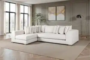 The Alameda Sectional Sofa features natural quartzite upholstery, reversible cushions, and a solid wood frame. Displayed in a transitional living room with neutral décor, this sofa highlights its oversized bench seating and included accent pillows.