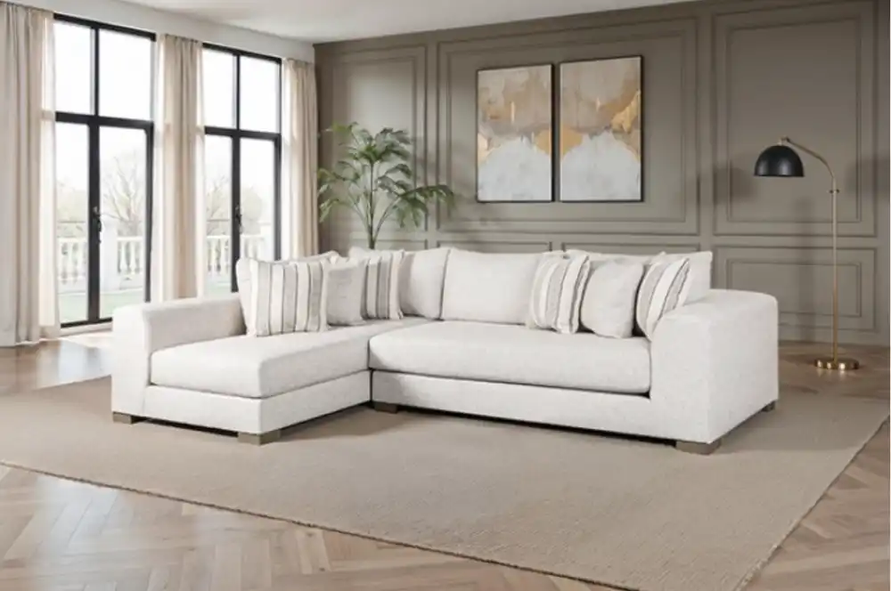 The Alameda Sectional Sofa features natural quartzite upholstery, reversible cushions, and a solid wood frame. Displayed in a transitional living room with neutral décor, this sofa highlights its oversized bench seating and included accent pillows.