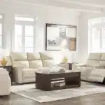 Dahlmoore 3-piece living room set featuring a power sofa, loveseat, and recliner in almond-tone top grain leather, displayed in a modern, light-filled room at the furniture store Tampa.