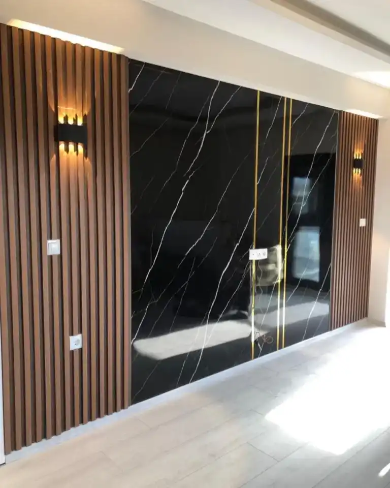 Black PVC marble sheet applied on walnut fluted wall panel, used as a modern TV background design.