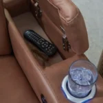 Close-up of the Clean-Slate Power Reclining Sofa armrest console storage, showing the hidden compartment, illuminated cup holder, and an inserted glass.