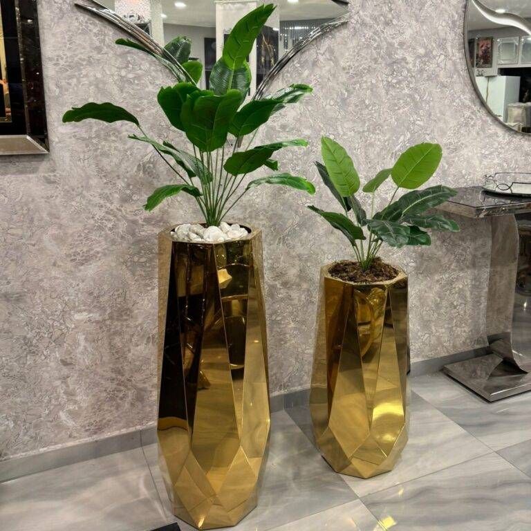 Two large gold geometric planters with lush green plants, adding a modern and luxurious touch to the interior decor.