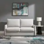 Jinn Modern Sleeper Sofa in Beige Chenille, styled as a couch in a contemporary living room with art and a table lamp.